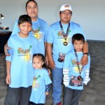 A family wearing matching blue shirts and medals.