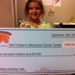 A girl holding up a large check for $ 3 0 0.