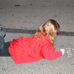 A little girl in red is laying on the ground
