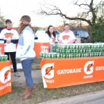A group of people standing around a row of gatorade bottles.