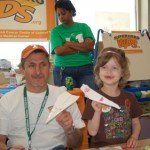 A man and girl holding paper planes at an event.