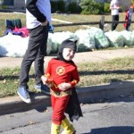 A young boy dressed as the flash is walking down the street.