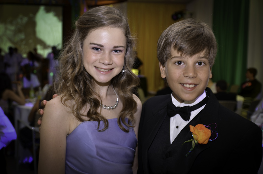 A young couple posing for the camera at their prom.