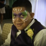 A boy with face paint and a flower in his hair.
