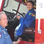 A man and boy in the driver 's seat of a fire truck.