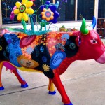 A colorful cow with flowers on the back of it.