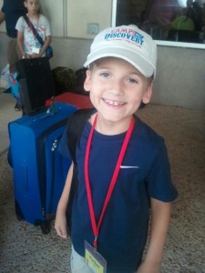 A young boy wearing a hat and holding a red lanyard.