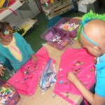 Two children are making bags of colorful paper.
