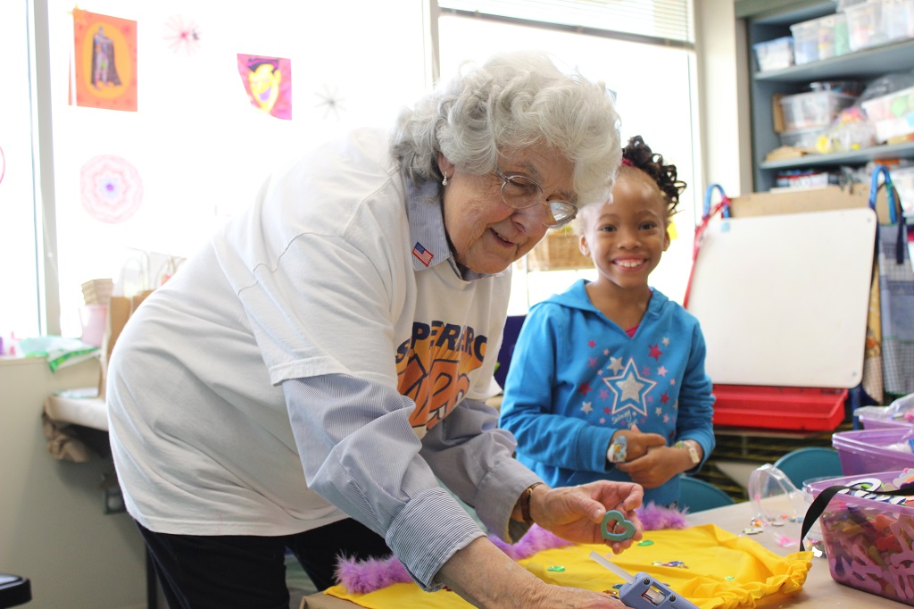 A woman cutting cake with a girl sitting next to her.