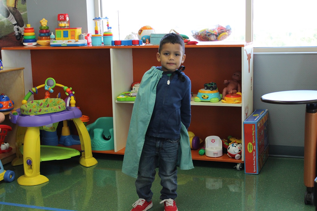 A young boy standing in front of shelves with toys.
