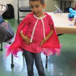 A little boy in pink shirt and cape
