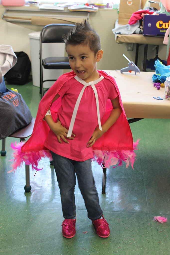 A little boy in pink shirt and cape