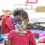 A little girl with some paper glasses on her face.
