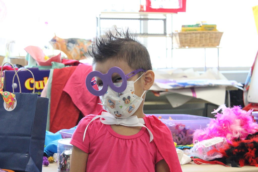 A little girl with some paper glasses on her face.