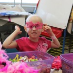 A young girl wearing pink glasses and holding onto her hair.