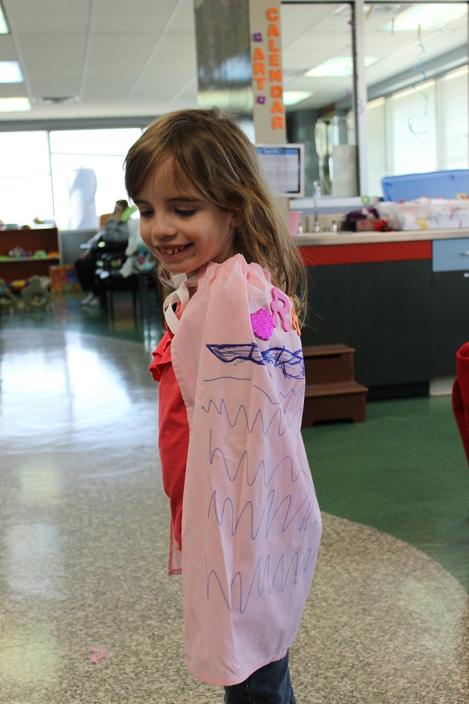 A little girl in pink shirt and red jacket.