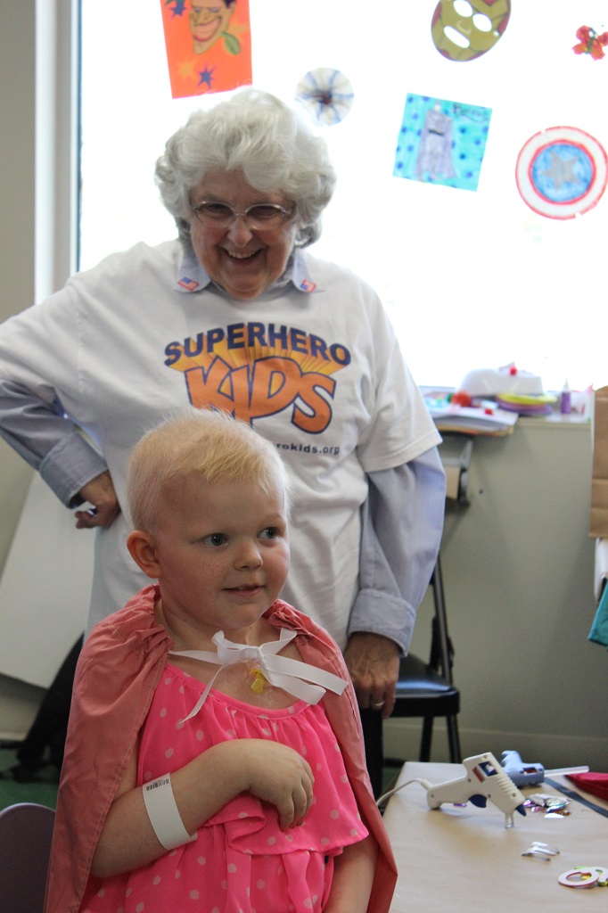 A woman standing next to a child in front of a chair.