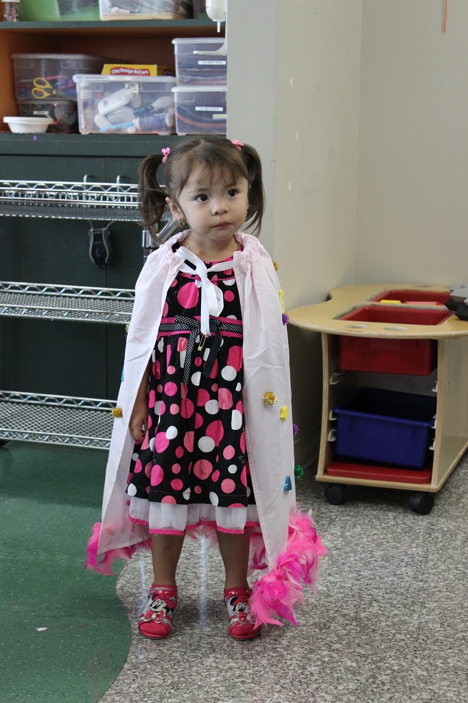 A little girl in a dress and cape