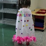 A little girl in a dress that says " makeliv ".