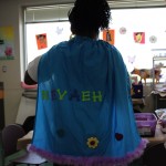 A person wearing a cape with the name " ryyeh " written on it.