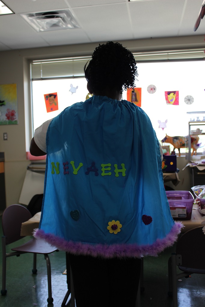 A person wearing a cape with the name " ryyeh " written on it.
