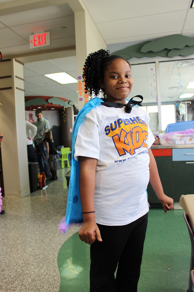 A girl in a white shirt and blue cape