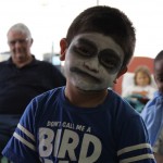 A boy with face paint is smiling for the camera.