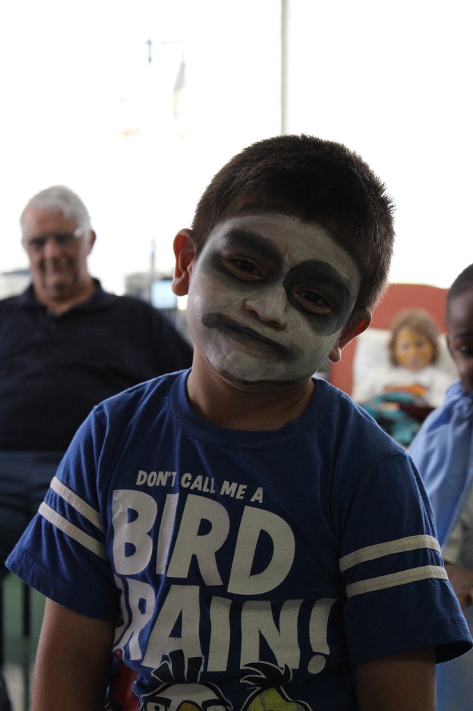 A boy with face paint is smiling for the camera.