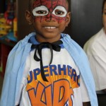 A boy with face paint and a cape.