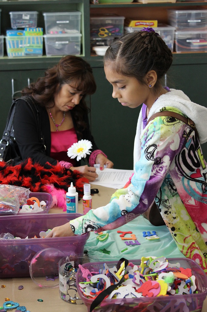 A woman and girl making crafts at table.