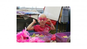A young girl with pink glasses and hair in her hands.