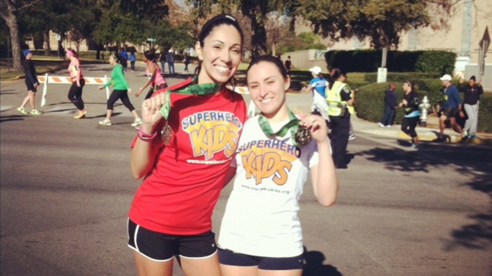 Two women standing next to each other holding medals.
