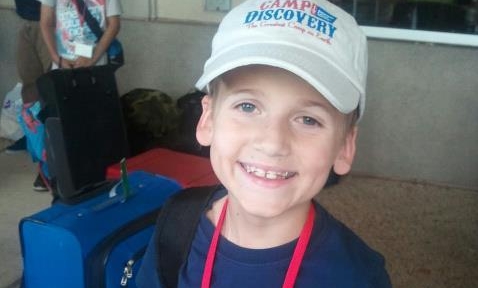 A young boy wearing a white hat and smiling.